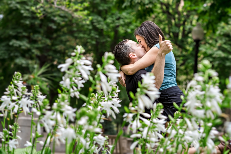 A man lifts his fiance up for a kiss while giving a thumbs up